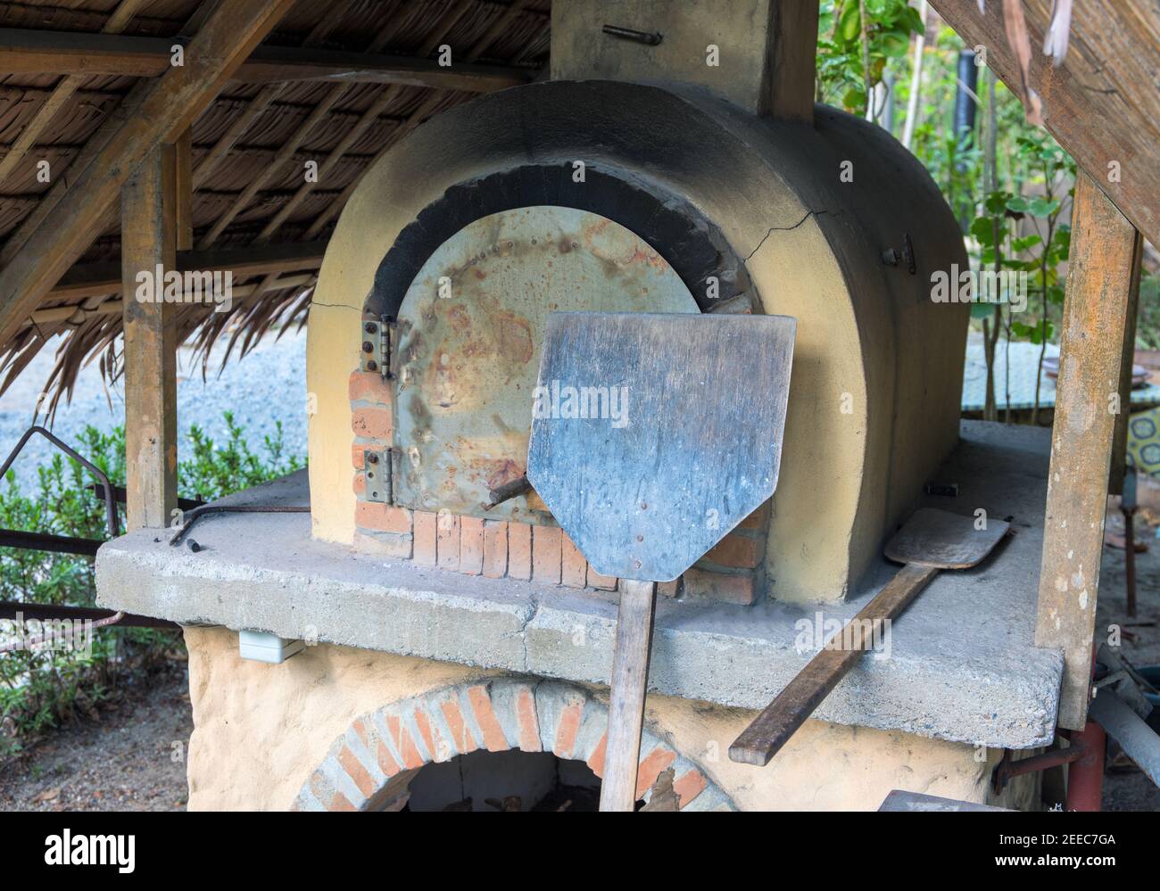 Alter Ofen mit Holzbackwerkzeugen. Pizza und Brot Kochen im Holzofen. Keramik-Steinofen im Vintage-Stil. Ländliche Bäckerei. Authentische Handwerkskunst Stockfoto