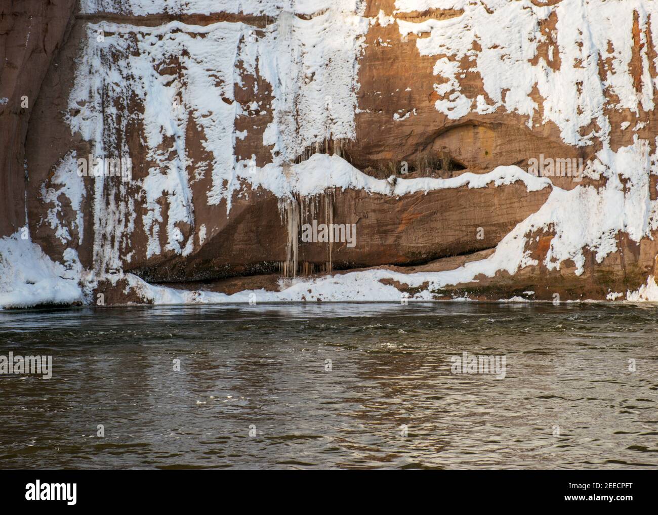 Schöner sonniger Tag, Landschaft mit roten Sandsteinfelsen, die mit Schnee verschneit sind, Eisfall an der Felswand, gefrorener Fluss, Gauja, Kuku Klippen, Lettland Stockfoto