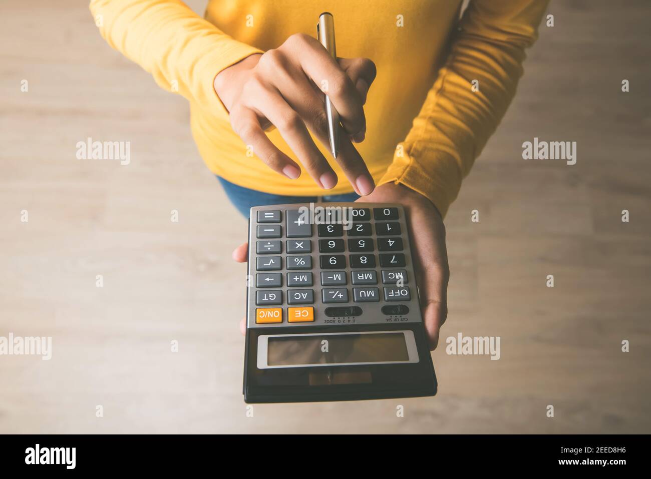 Frau Unternehmerin mit einem Rechner mit einem Stift in der Hand, Berechnung der finanziellen Kosten im Home Office Stockfoto