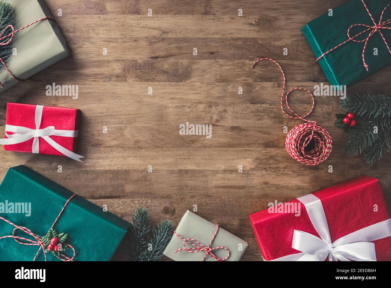 Draufsicht auf bunt dekorierten Geschenkboxen auf einem Holztisch mit Kiefer und Mistel, Bordüre Design Weihnachten Hintergrund mit Kopierraum in der Mitte Stockfoto