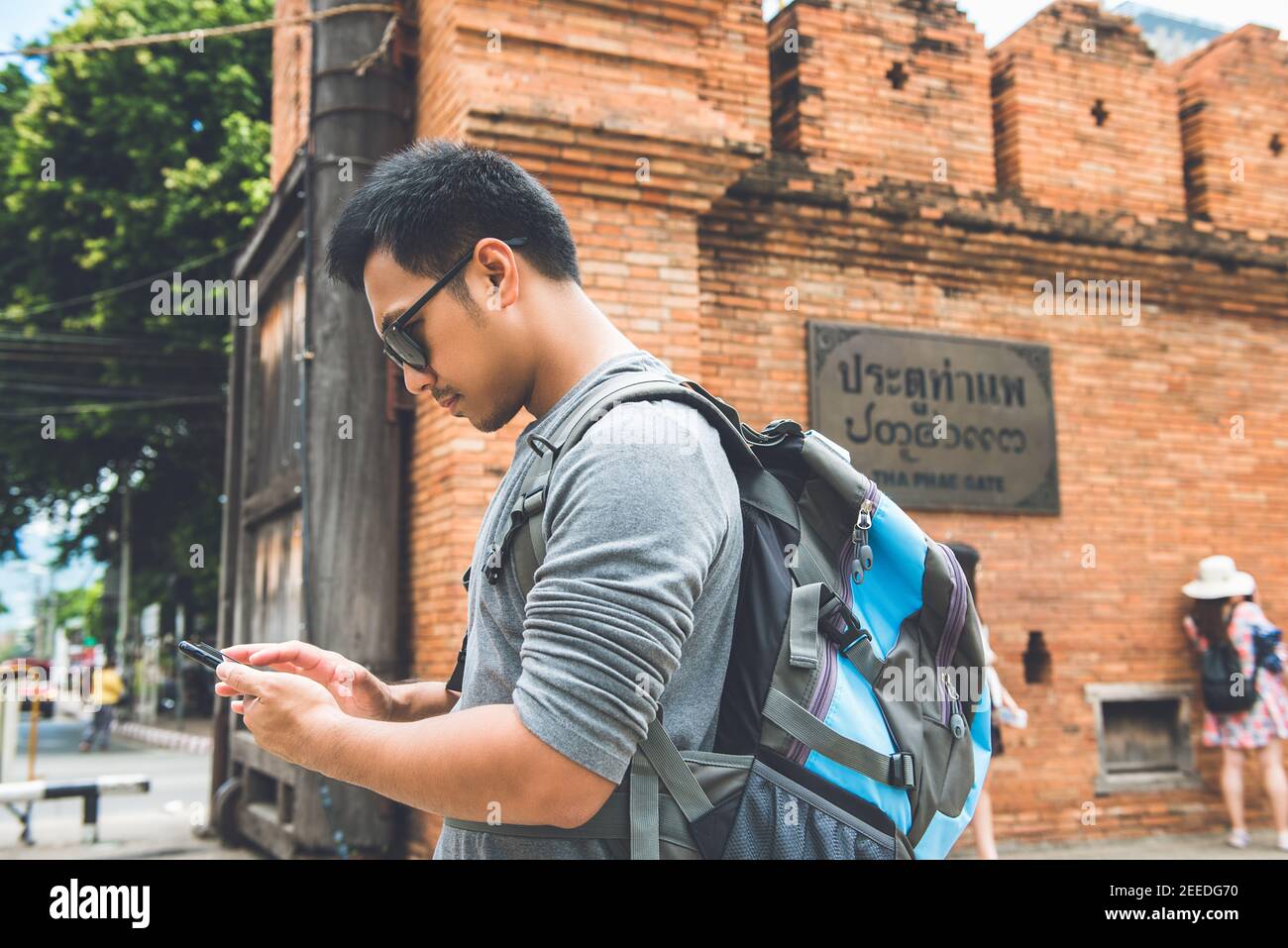 Asian Mann Tourist Backpacker mit Smartphone Suche nach Informationen während der Reise in Chiang Mai Thailand. Schild an der Wand sagte THA PHAE TOR Stockfoto Asian Mann Tourist Backpacker mit Smartphone Suche nach Informationen während der Reise in Chiang Mai Thailand. Schild an der Wand sagte THA PHAE TOR Stockfoto