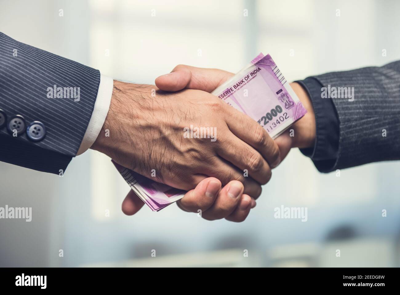 Geschäftsleute machen Handshake mit Geld, indische Rupie Währung, in den Händen - Bestechung und Korruption Konzept Stockfoto