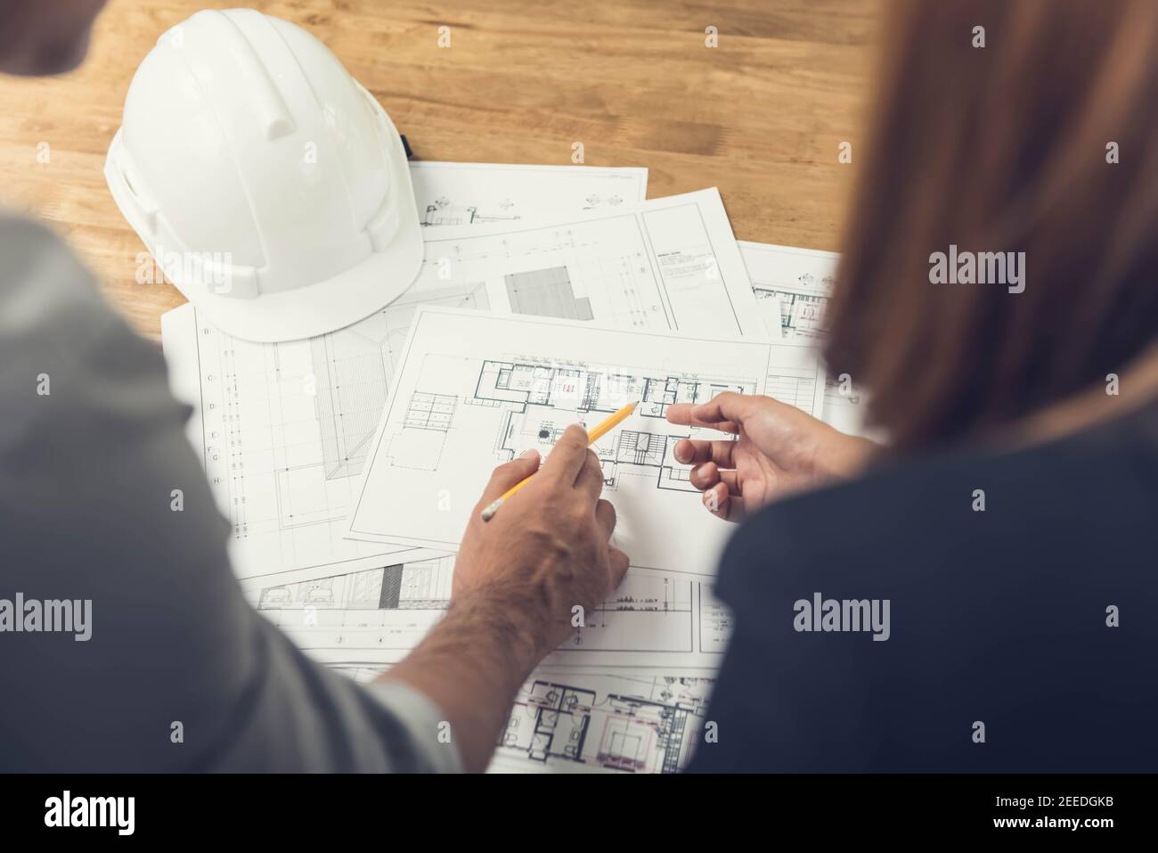 Architekten- oder Ingenieurteam, das ein Projektdesign anhand von Blaupausen im Büro diskutiert, bevor es die Baustelle besucht. Stockfoto
