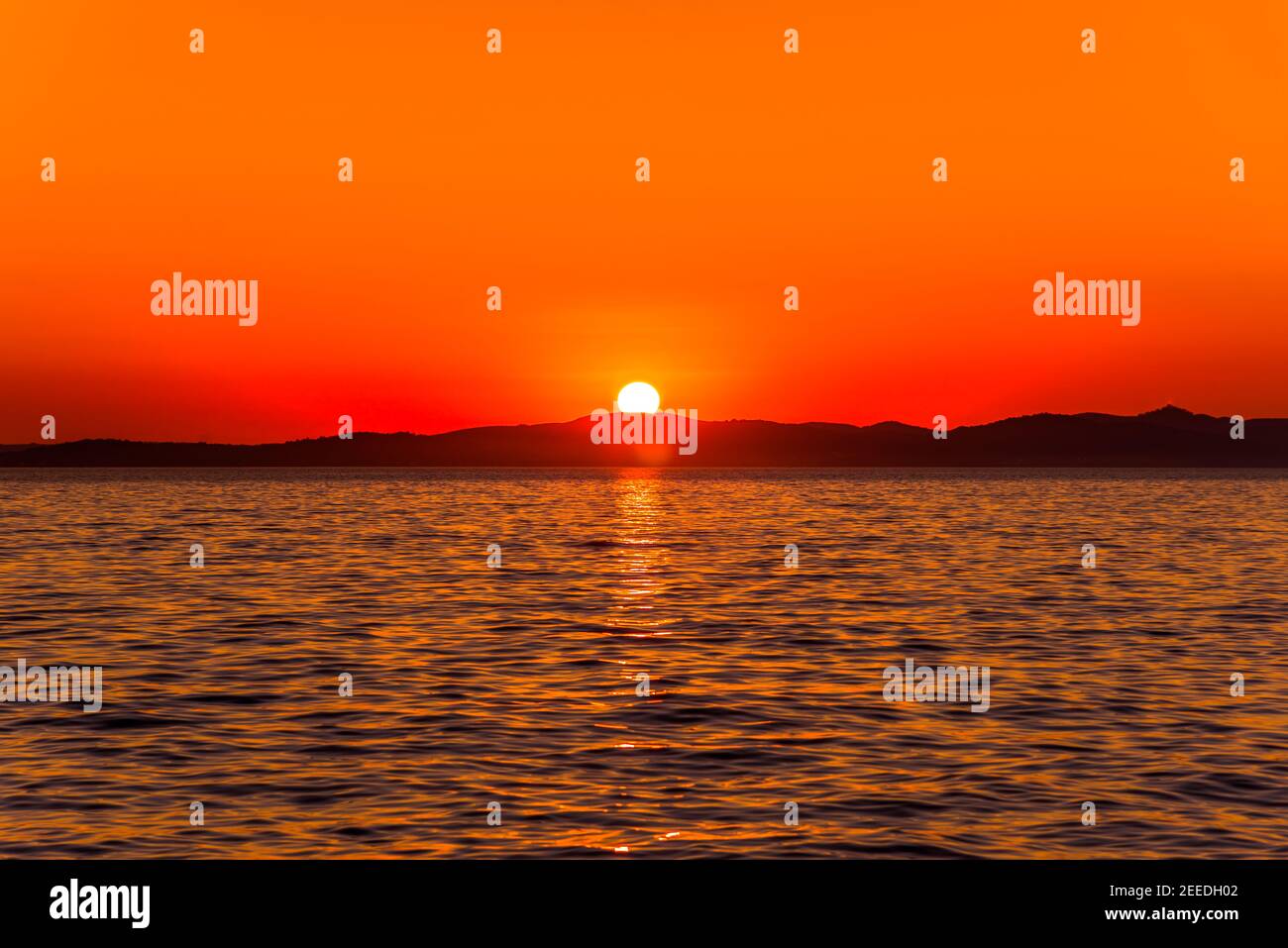 Schöne orange Sonnenuntergang über dem Meer mit Sonne auf den Bergen Horizont, Blick vom Strand in Zadar, Dalmatien, Kroatien, Europa Stockfoto