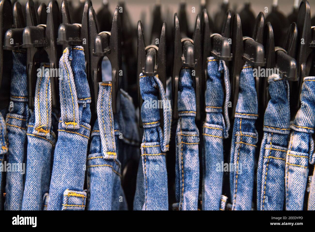 Blaue Jeans am Hang im Modehaus. Krawatte Dye Jeans Kleidung Foto. Unisex-Kleidung auf Kleiderbügel im Geschäft. Fashion Shop Black Friday Sale. Trendige Kleidung geht ab Stockfoto