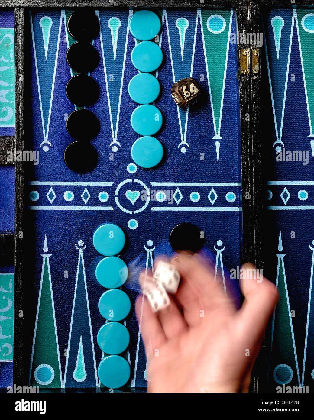 Ein Backgammon-Spiel auf einem bunten Brett, mit einer Hand, die Würfel rollt Stockfoto