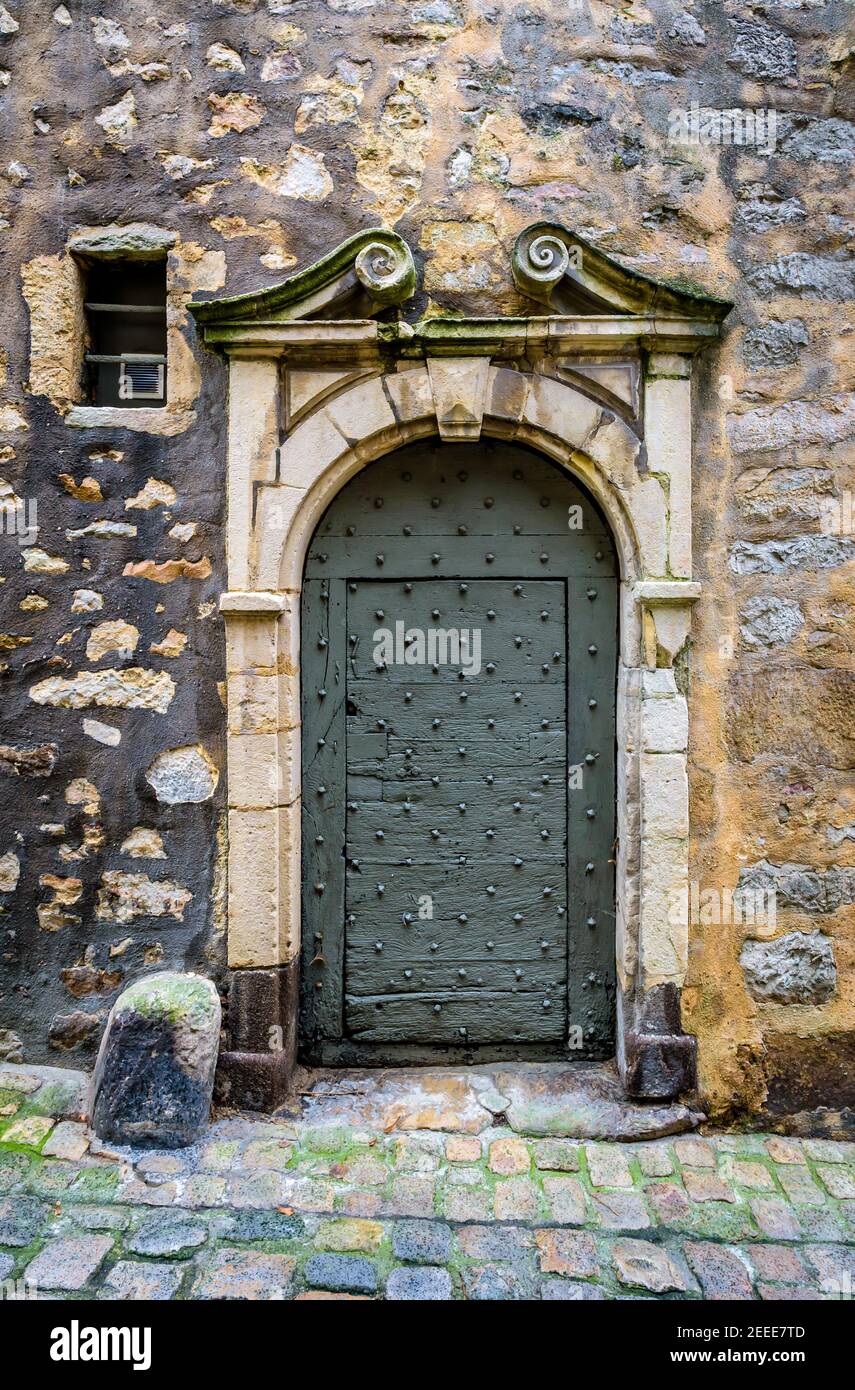 Vorderansicht der Eingangstür eines mittelalterlichen Stadthauses, mit einem gemeißelten Steinrahmen, in einer gepflasterten Straße des historischen Zentrums von Le Mans, Frankreich. Stockfoto