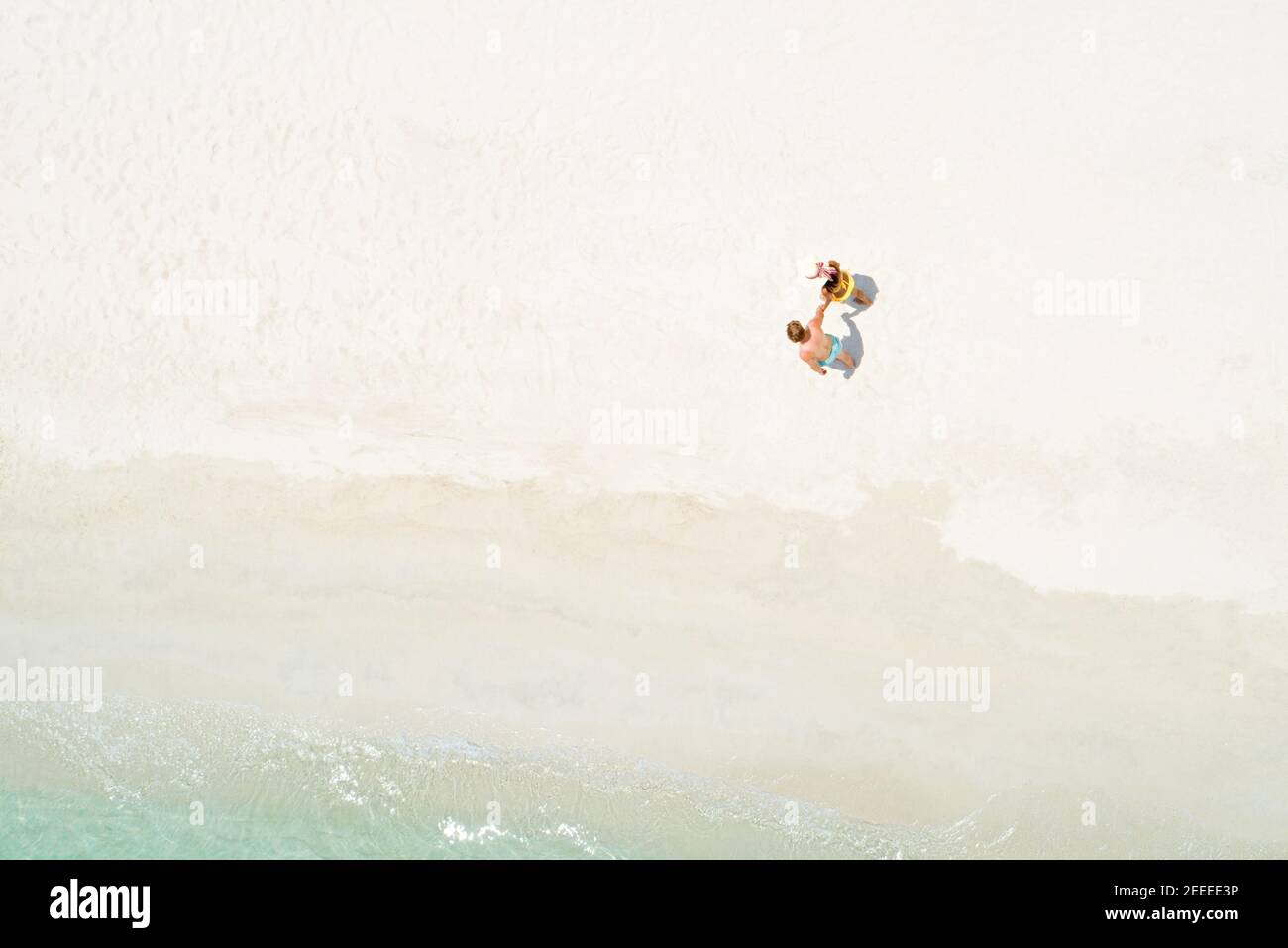 Flitterwochen-Paar mit der Hand am wunderschönen weißen Sandstrand Im Sommer - Drone-Aufnahme von oben Stockfoto