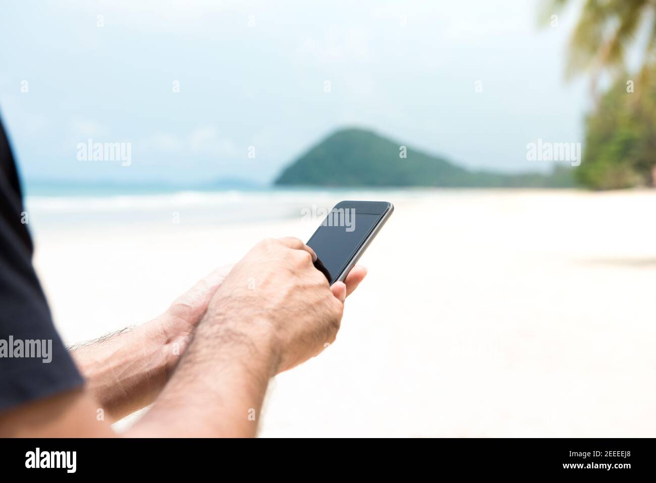 Männlicher Tourist mit Smartphone auf der Insel am Strand im Sommerurlaub - Mobile Roaming Konzept Stockfoto