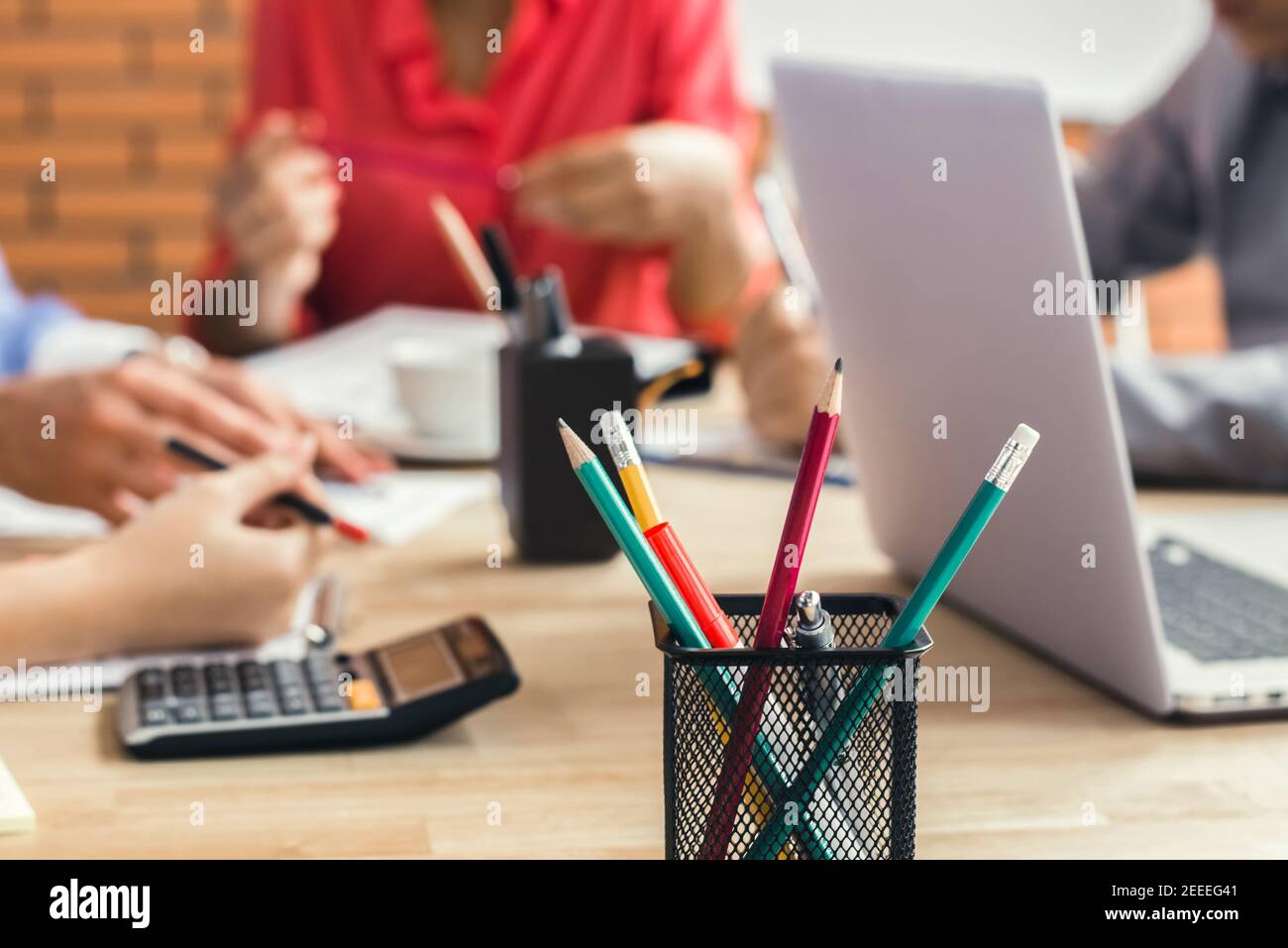 Bunte Bürobedarf mit Laptop-Computer auf dem Besprechungstisch mit Verwischen Sie Geschäftsleute im Hintergrund Stockfoto