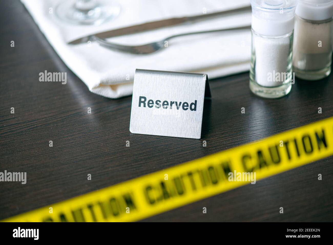 Achtung - gelbes Klebeband über dem Tisch im Café oder Restaurant und Schild reserviert. Soziale Distanzierung Stockfoto