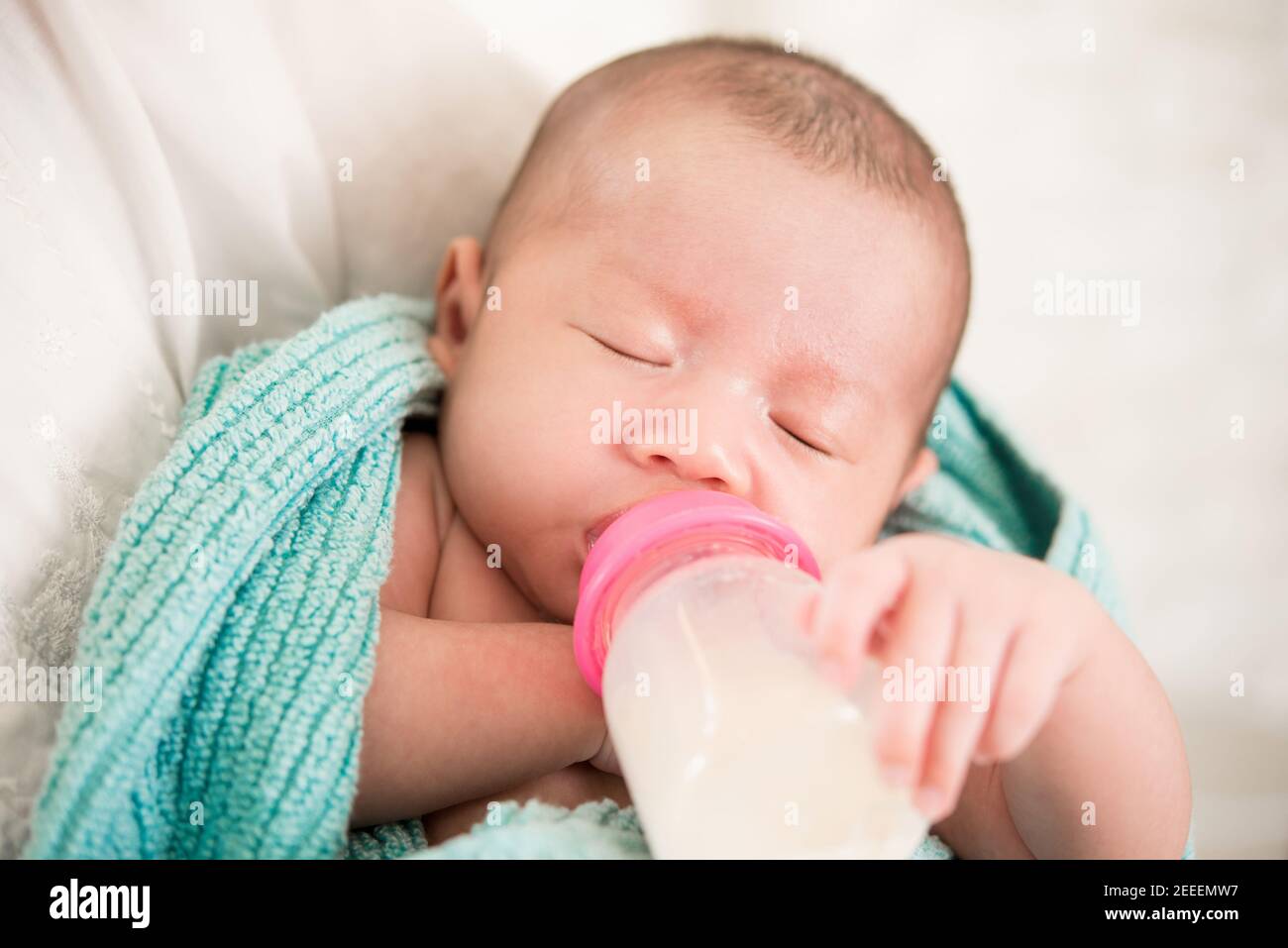 Schläfrig niedlichen Neugeborenen trinken Milch aus der Flasche in der Mutter Arme Stockfoto