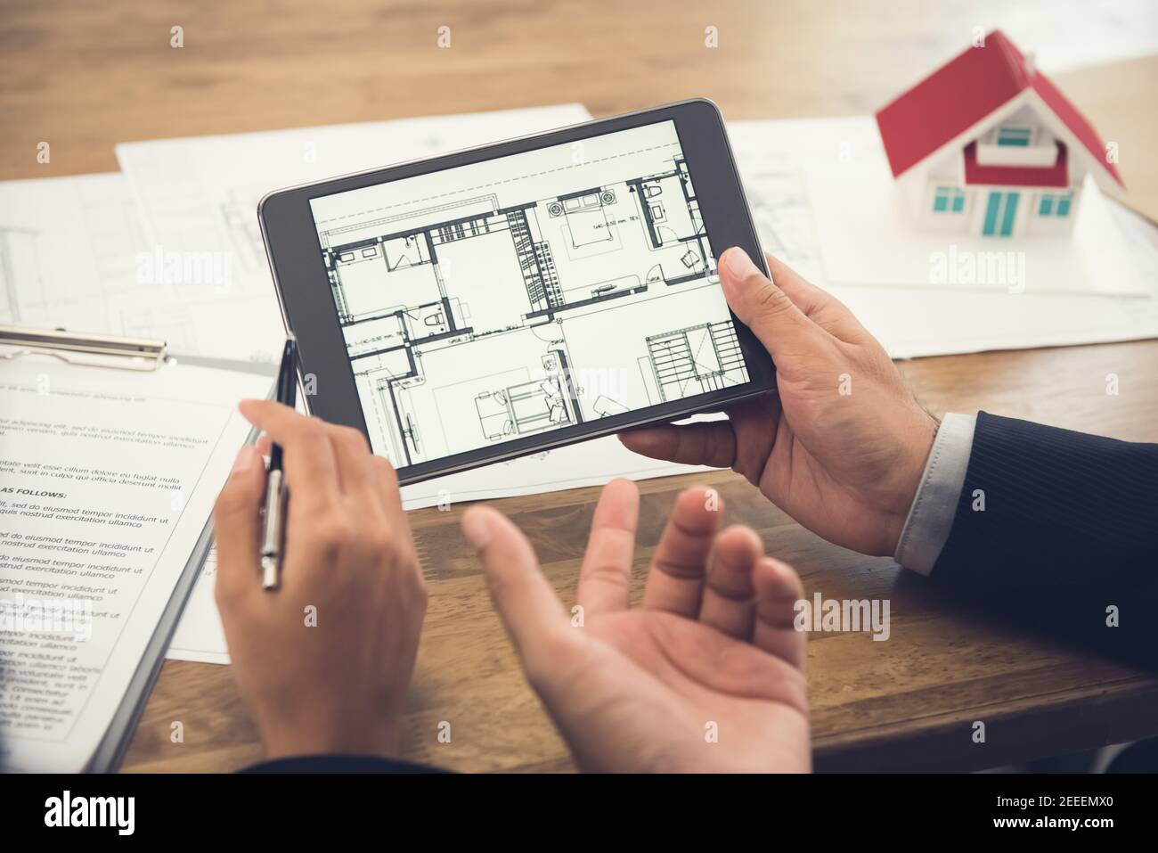 Immobilienmakler mit Client oder Architektenteam diskutieren Haus Grundriss auf Tablet-Computer-Bildschirm Stockfoto