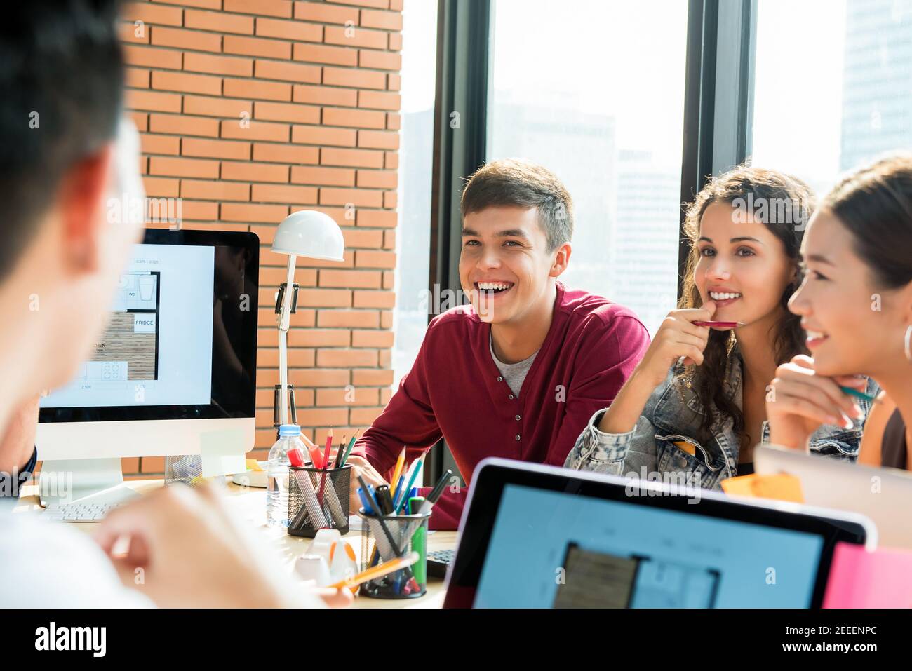 Das junge Innenarchitektenteam lächelt und schaut ihren Kollegen an In der Sitzung - Glück bei der Arbeit Konzept Stockfoto