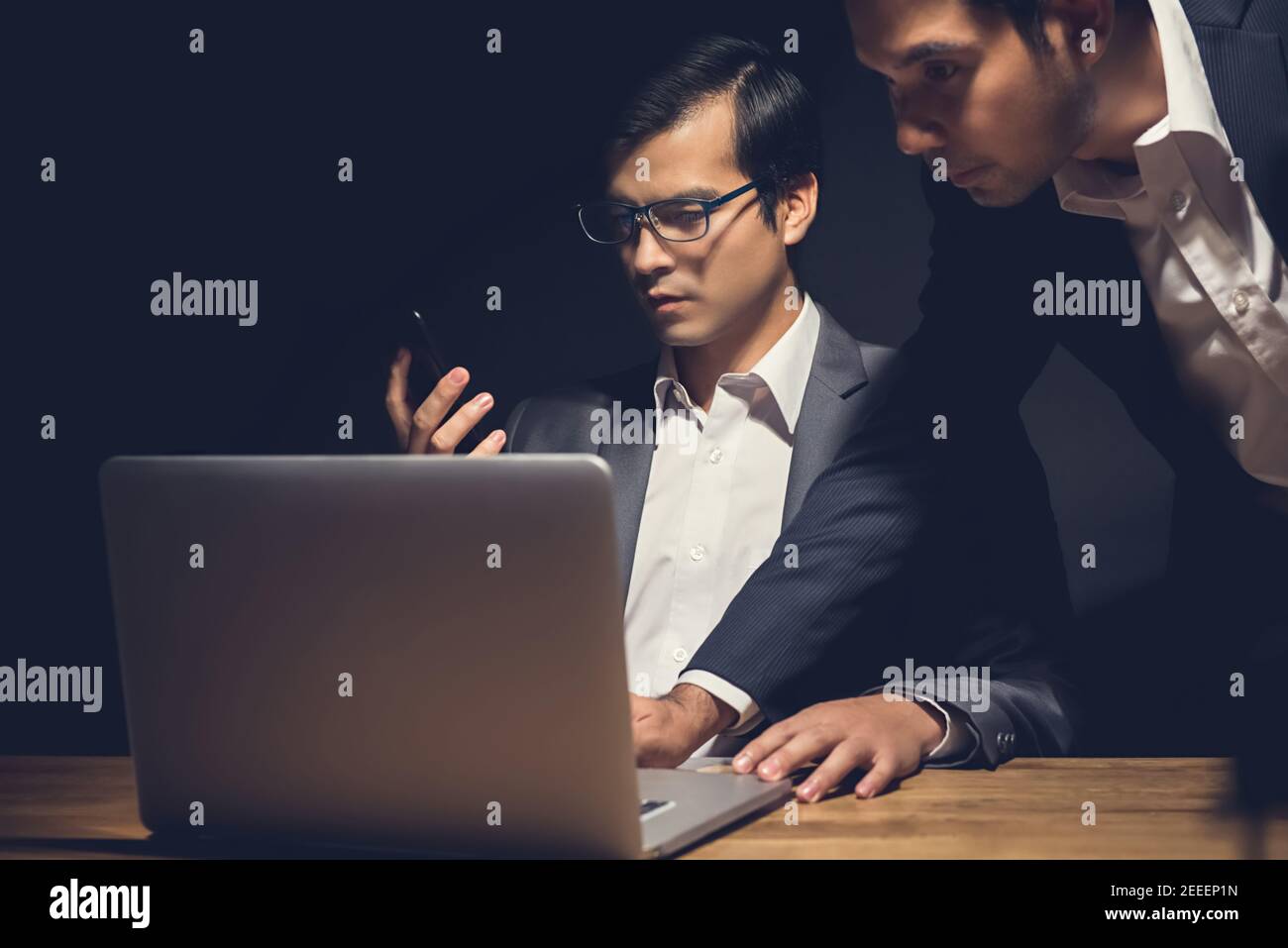 Geschäftsleute, die einen Laptop benutzen, arbeiten spät in der Nacht im Dunkeln Raum - Workaholic und Hacker-Konzept Stockfoto