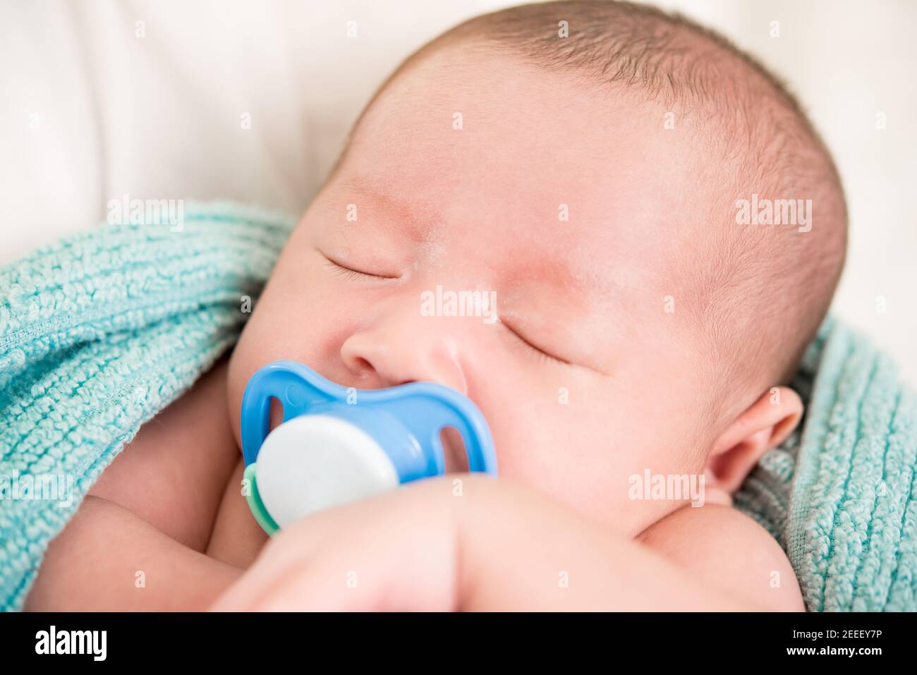 Liebenswert schlafen neugeborenes Baby mit Dummy im Mund Stockfoto