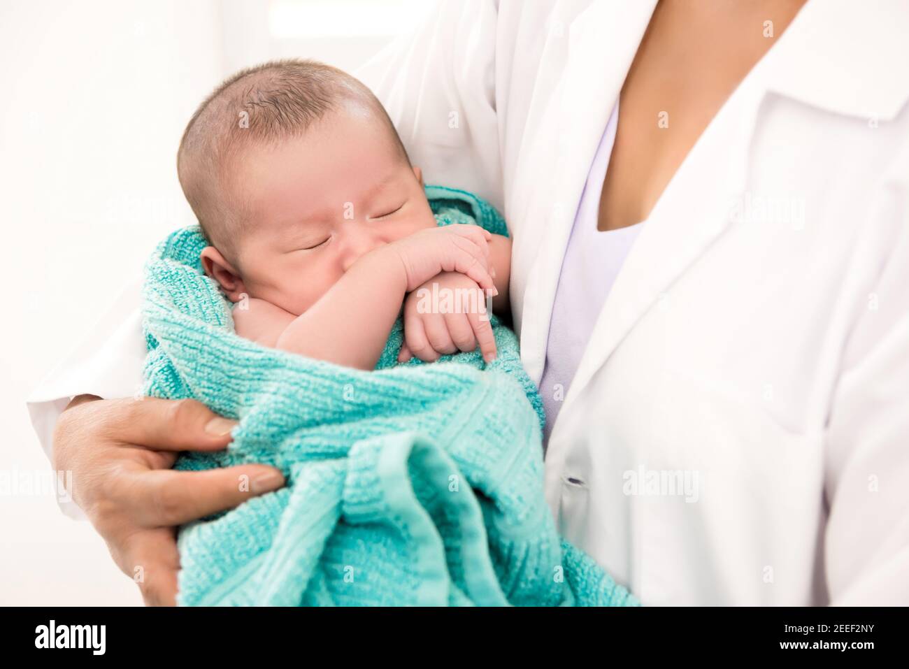 Arzt hält das schlafende Neugeborene in den Armen Stockfoto