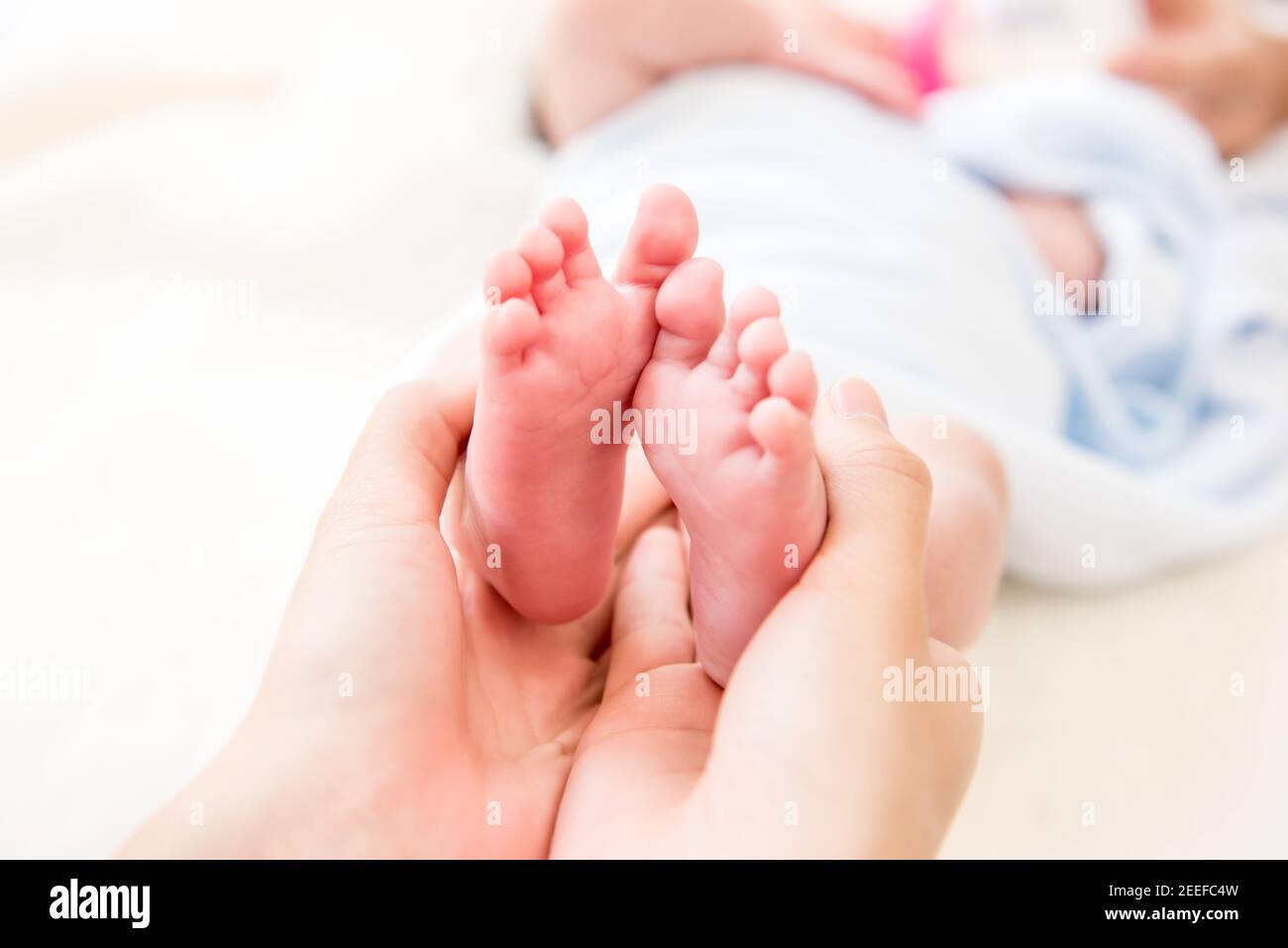 Mutter Hände sanft halten kleine Baby Füße mit Sorgfalt Stockfoto