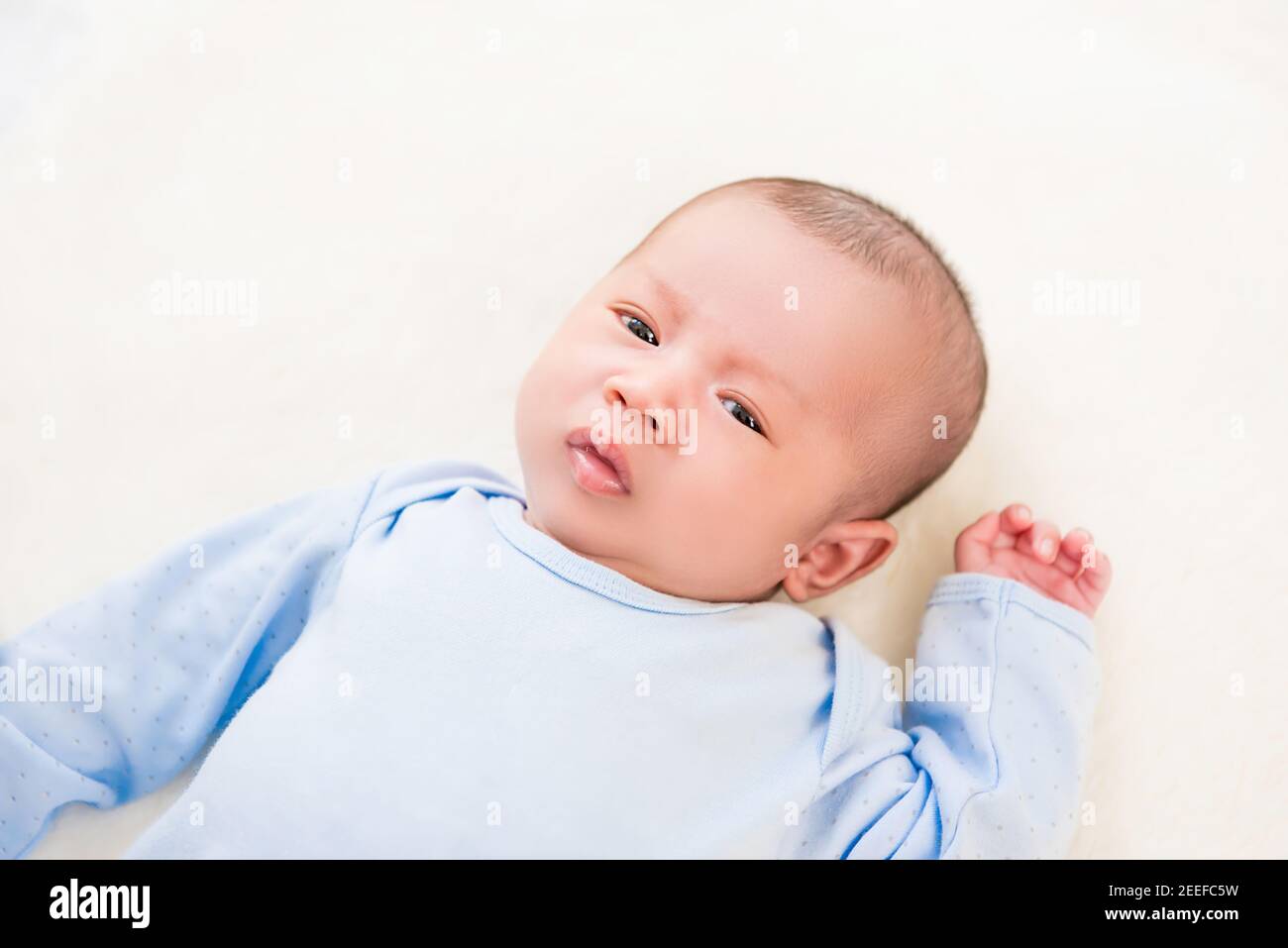 Niedliches neugeborenes Baby liegt auf weißem Laken - Draufsicht Stockfoto