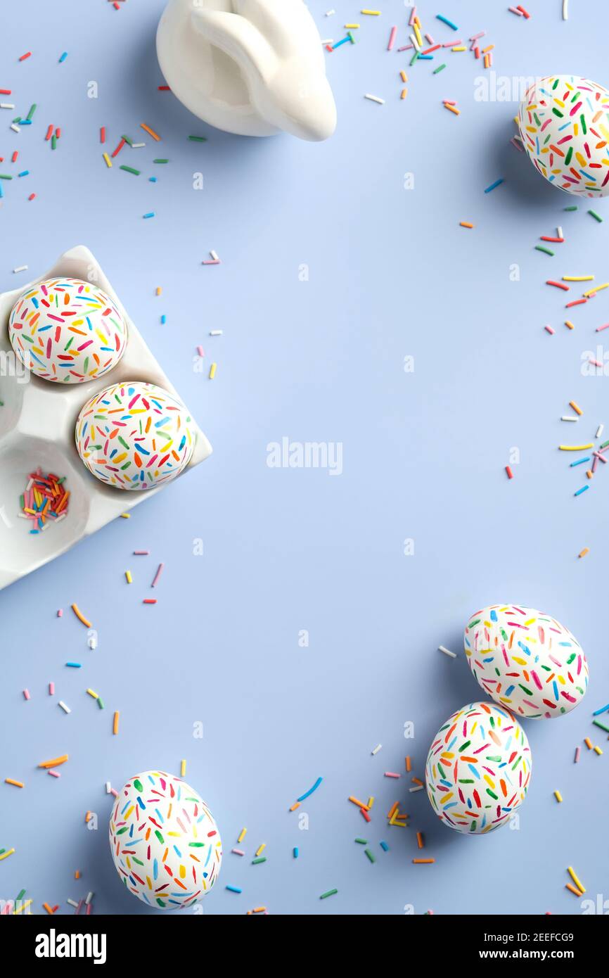 Frohe Ostern Karte. Rahmen aus Osterhase und bunt gesprenkelten Ostereiern auf blauem Hintergrund. Vertikales Banner-Mockup für Social Media-Geschichten. Stockfoto