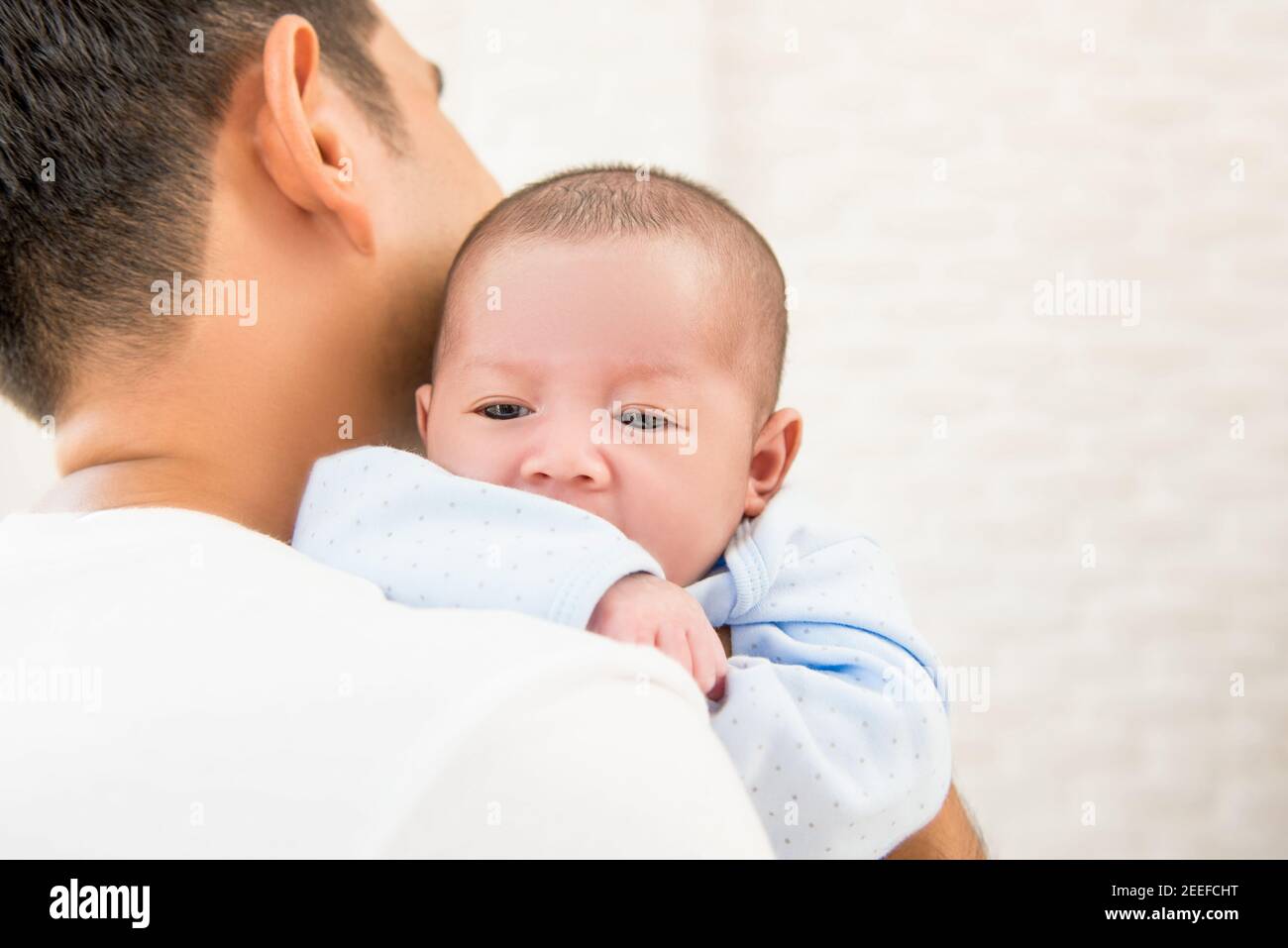 Neuer Vater hält sein liebenswertes kleines Baby über der Schulter Stockfoto