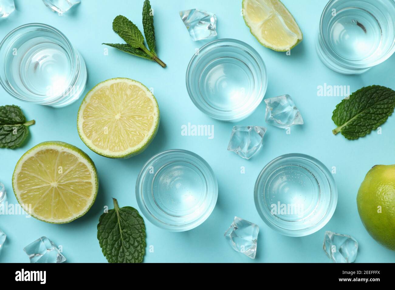 Schüsse, Limettenscheiben, Minze und Eiswürfel auf blauem Hintergrund, Draufsicht Stockfoto