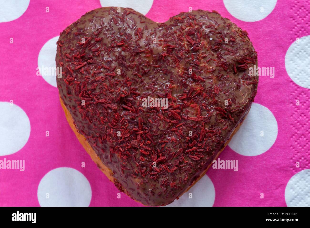 Herzförmiger Donut für den Valentinstag aus der Bäckerei von Marks & Spencer auf rosa Tupfen Serviette Serviette gesetzt Stockfoto