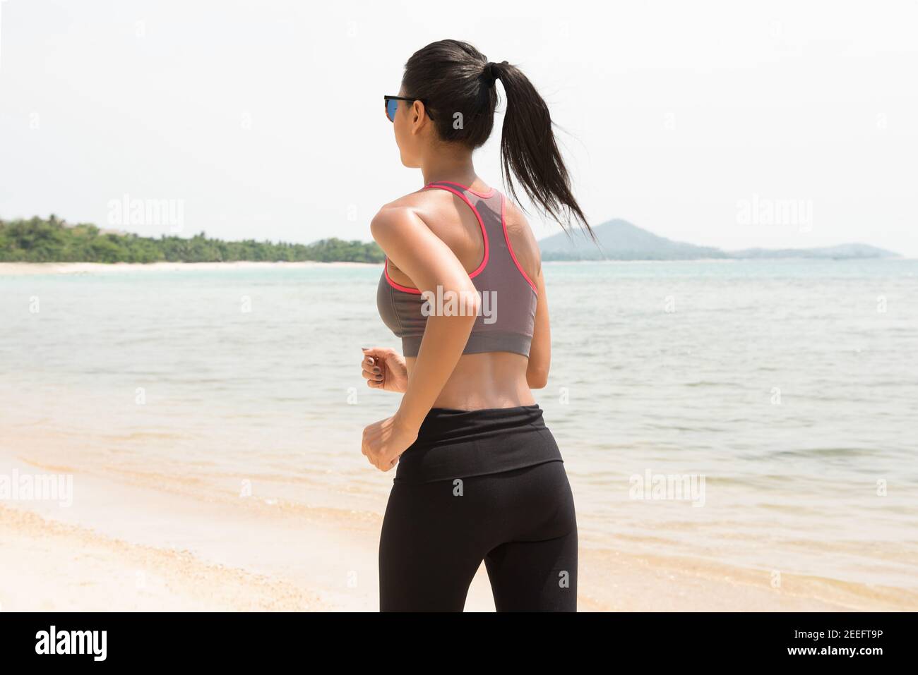 Frau läuft am Strand im Sommer - Rückansicht Stockfoto