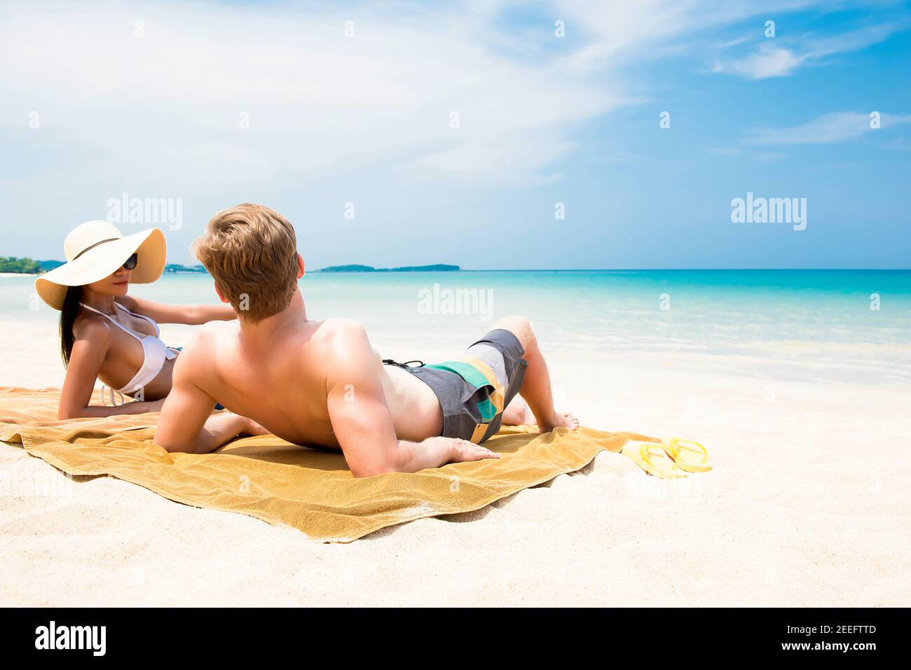 Pärchen liegen am weißen Sandstrand und entspannen sich und nehmen ein Sonnenbaden im Sommer Stockfoto