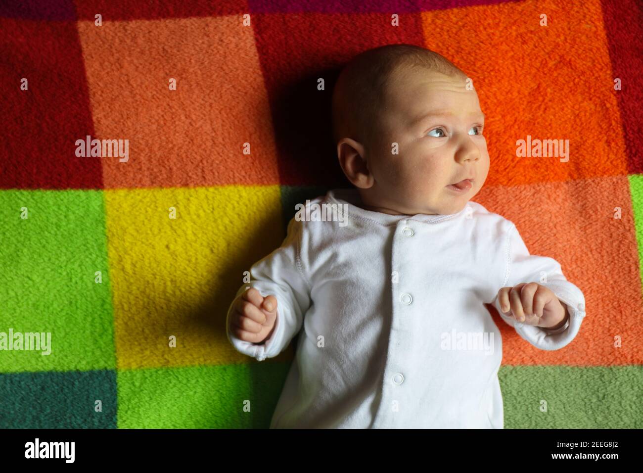 Kleine kaukasische Baby junge 2-3 Monate alt Porträt Seitenansicht auf einer bunten Decke. Suchen das Licht Stockfoto