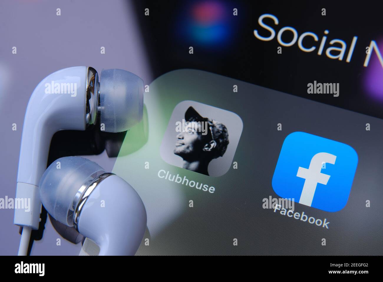 Kopfhörer werden oben auf dem Bildschirm neben der Clubhouse-App und der Facebook-App platziert. Konzept für den Wettbewerb. Stafford, Vereinigtes Königreich - 15. Februar 2021. Stockfoto