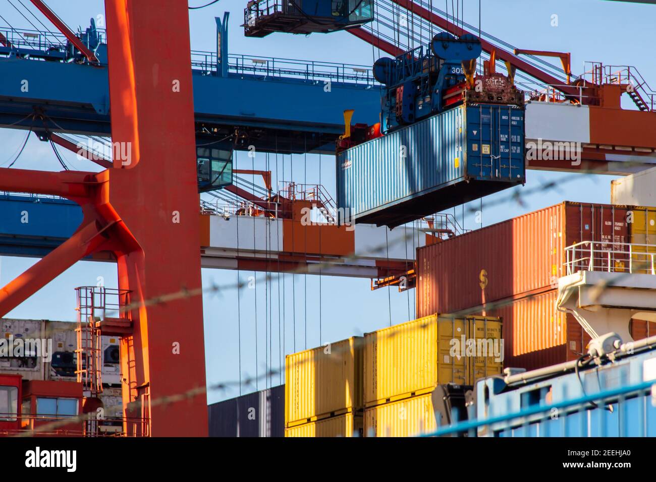 Containerschiff beim Verladen am Hafen mit einem Kran Heben eines Containers an einem sonnigen Tag Stockfoto