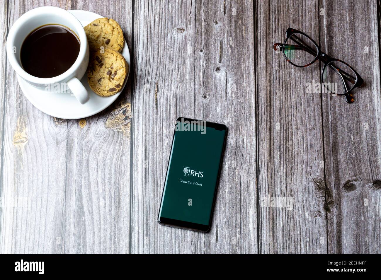 Ein Handy oder Handy auf einem Holz gelegt Tabelle mit geöffneter RHS-App auf dem Bildschirm Stockfoto