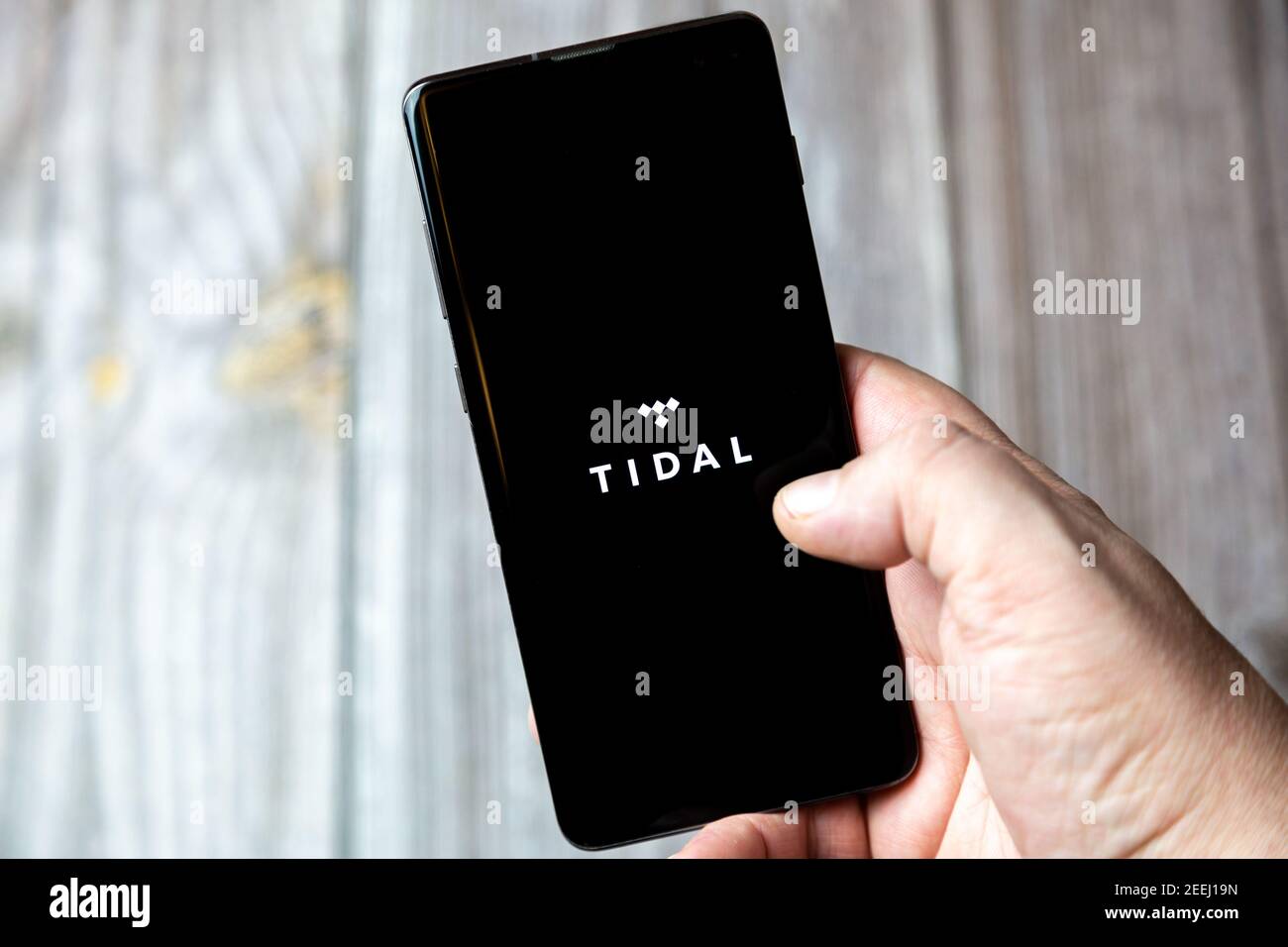 Ein Mobiltelefon oder Mobiltelefon, das in einem gehalten wird Hand mit der Tidal App auf dem Bildschirm geöffnet Stockfoto
