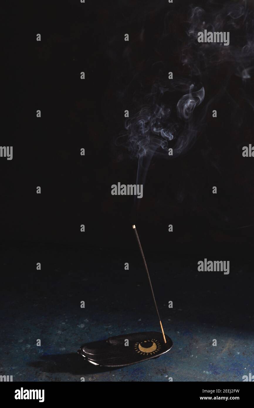 Ein Räucherstäbchen auf einer Handballenauflage raucht auf Schwarzer Hintergrund Stockfoto