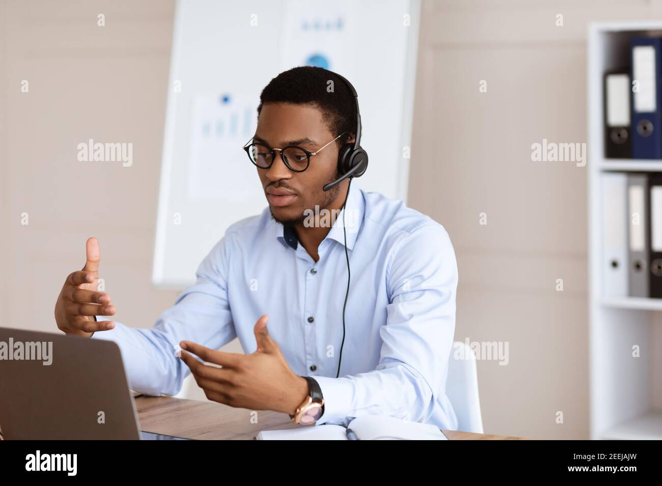 Afroamerikanischer Mann mit Videoanruf über Laptop, Büroinnenraum Stockfoto