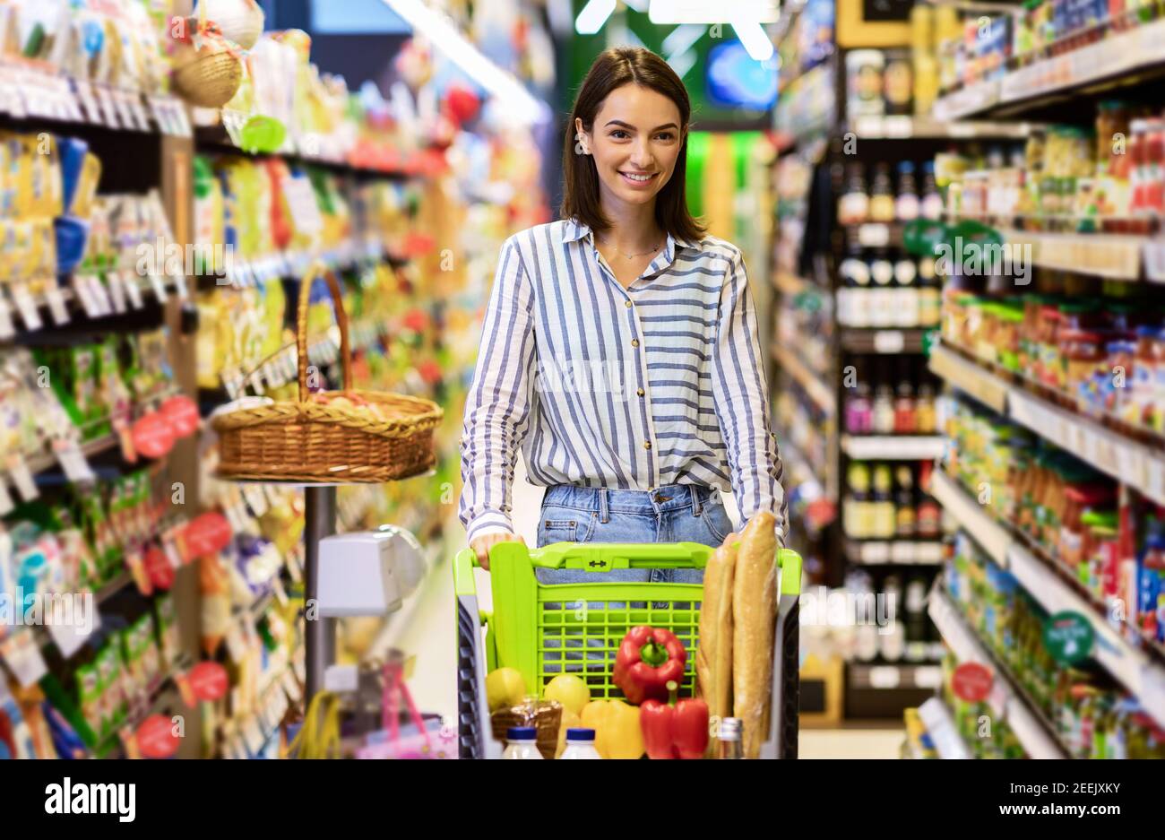 Junge Frau einkaufen im Supermarkt mit Trolley-Wagen Stockfoto