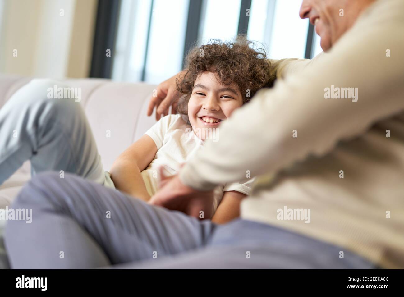 Glücklicher lateinischer Vater mittleren Alters verbringt Zeit mit seinem Sohn, spielt mit dem Kind im Wohnzimmer zu Hause. Familie, Freizeit, Vaterschaft Konzept Stockfoto