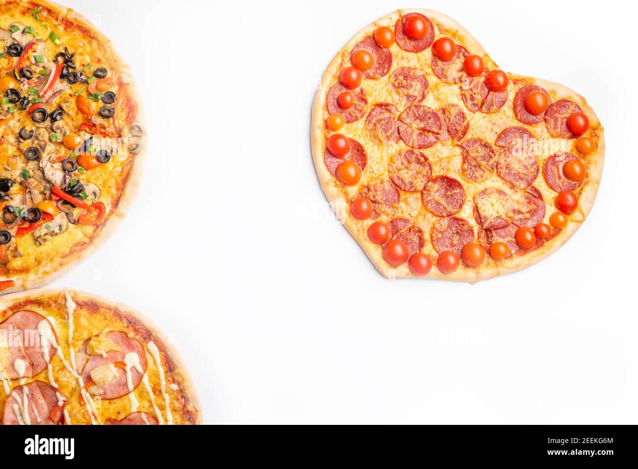 Drei verschiedene Arten von Pizzen, rund und Herz auf weißem Hintergrund mit Kopierraum, Salami, Pilze, Tomaton, Pepperoni, Kirschtomate und Stockfoto