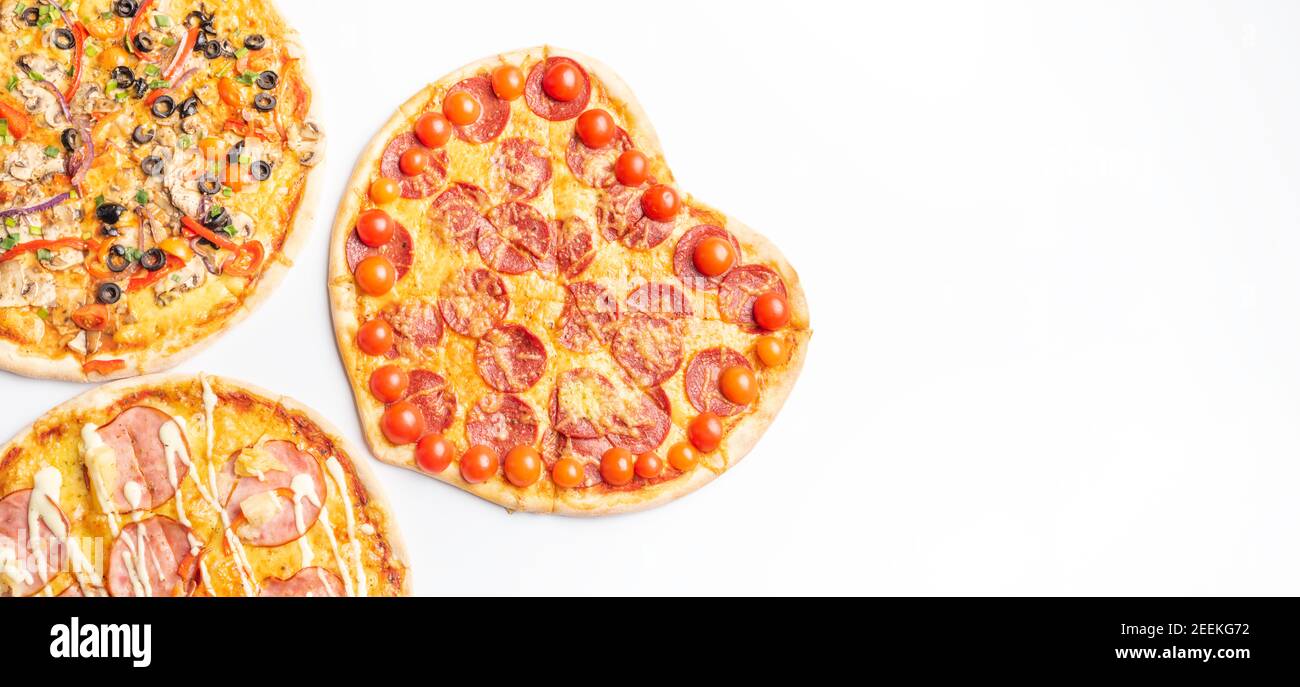 Drei verschiedene Arten von Pizzen, rund und Herz auf weißem Hintergrund mit Kopierraum, Salami, Pilze, Tomaton, Pepperoni, Kirschtomate und Stockfoto