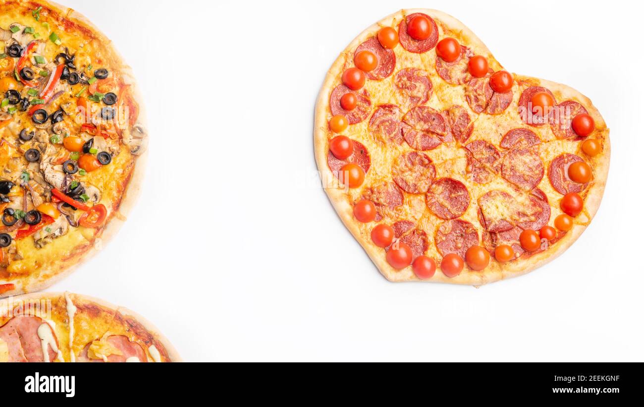 Drei verschiedene Arten von Pizzen, rund und Herz auf weißem Hintergrund mit Kopierraum, Salami, Pilze, Tomaton, Pepperoni, Kirschtomate und Stockfoto