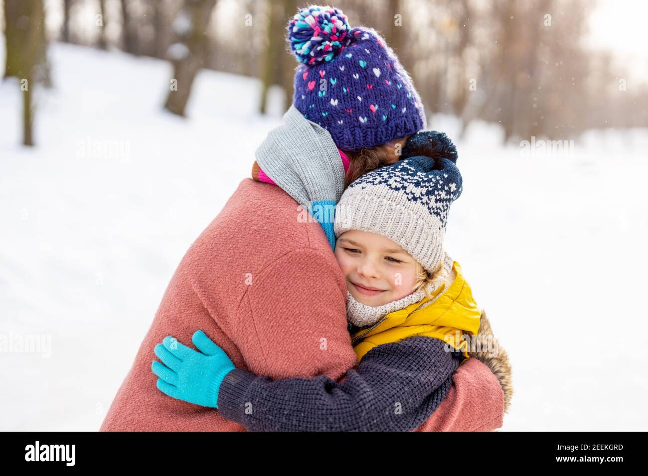 Mutter und Sohn umarmen sich im Schnee Stockfoto