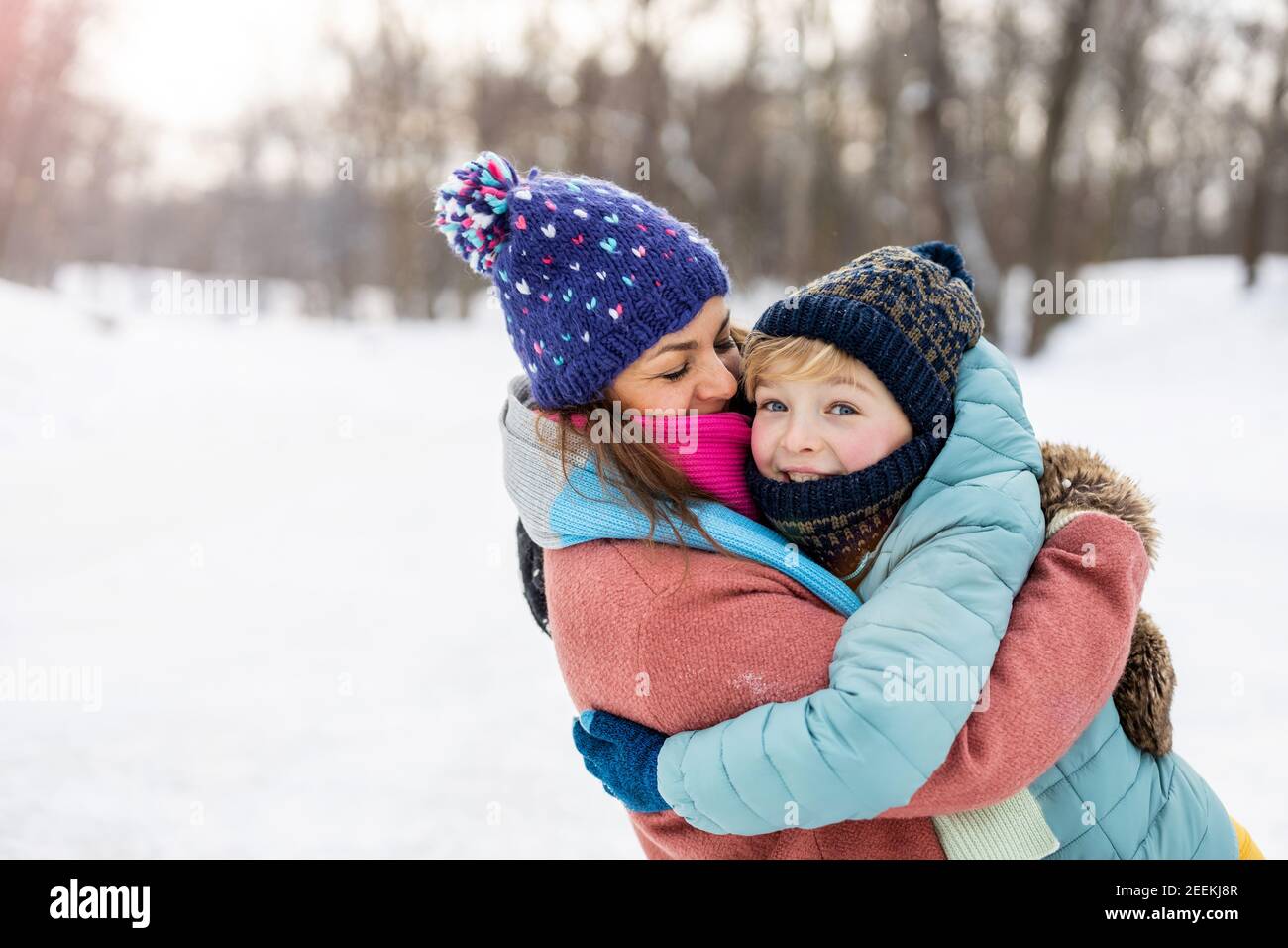 Mutter und Sohn umarmen sich im Schnee Stockfoto