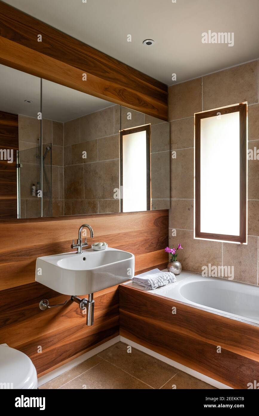 Badezimmer in amerikanischem Walnussholz mit Spiegelschränken, die eine Illusion vermitteln Platz Stockfoto