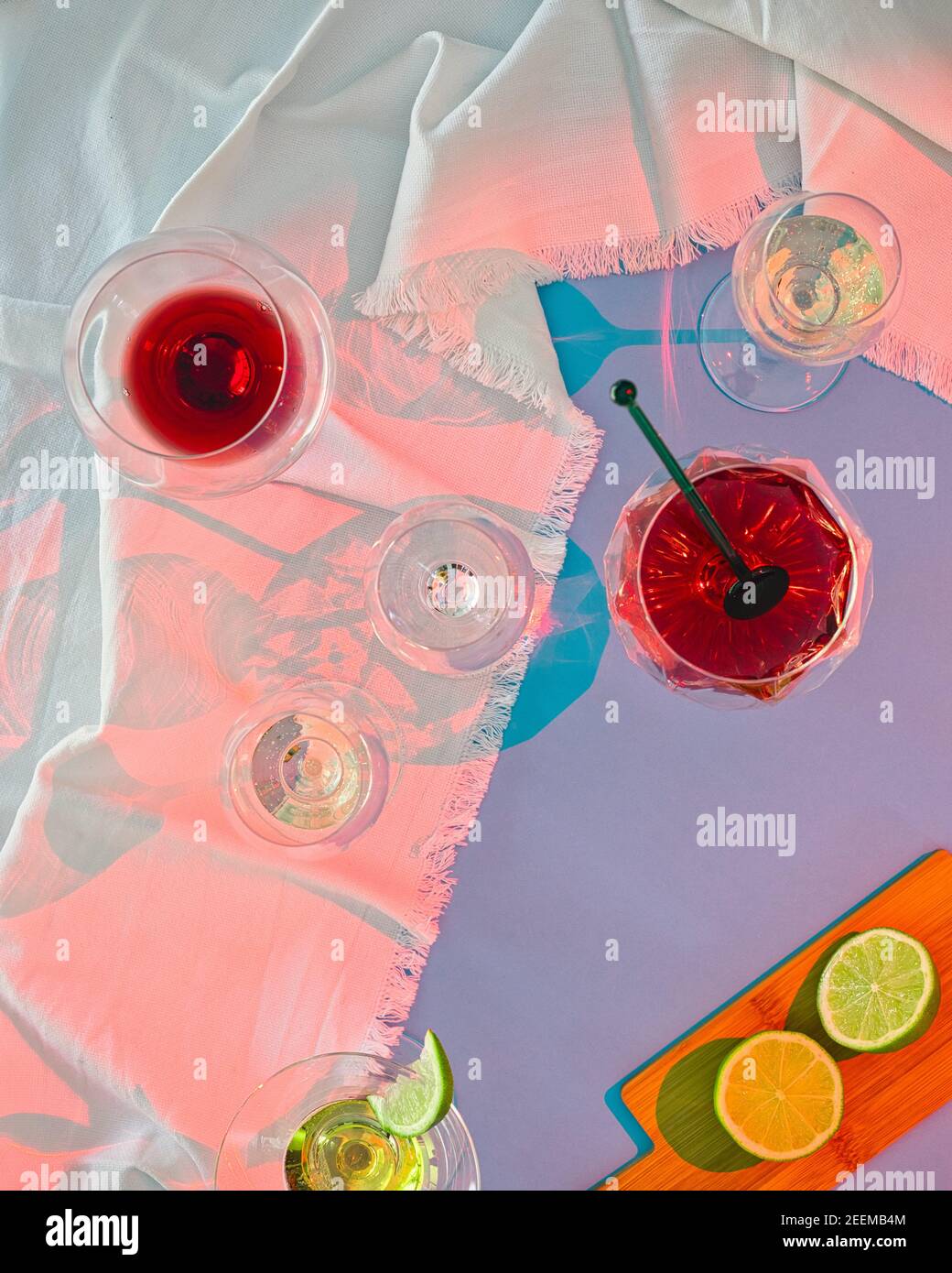 Auf blauem Hintergrund und zerknitterter weißer Tischdecke mehrere Gläser Von Wein und Spirituosen mit Party Stockfoto