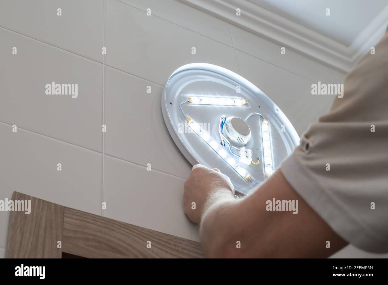 Ein Mann installiert eine LED-Lampe im Badezimmer. Reparatur und Verbesserung der Wohnung. Stockfoto