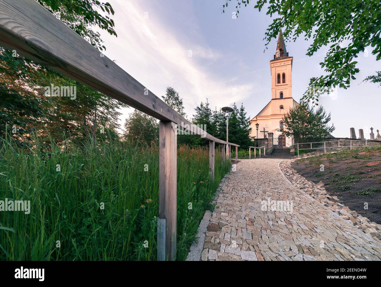 Kleine christliche Kirche aus dem 18. Jahrhundert in der goldenen Stunde mit einem Holzgeländer davor. Alte Kirche des Heiligen Ignatius in Malenovice, Tschechische Republik Stockfoto