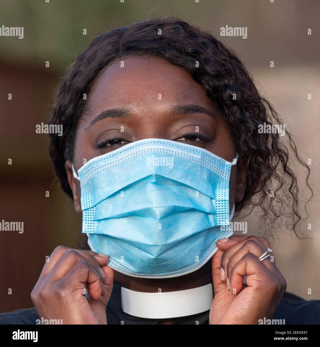 England, Großbritannien, Dezember 2020. Ein schwarzer Minister, der während des Coronavirus-Ausbruchs eine medizinische Schutzmaske und ein weißes Halsband trägt Stockfoto