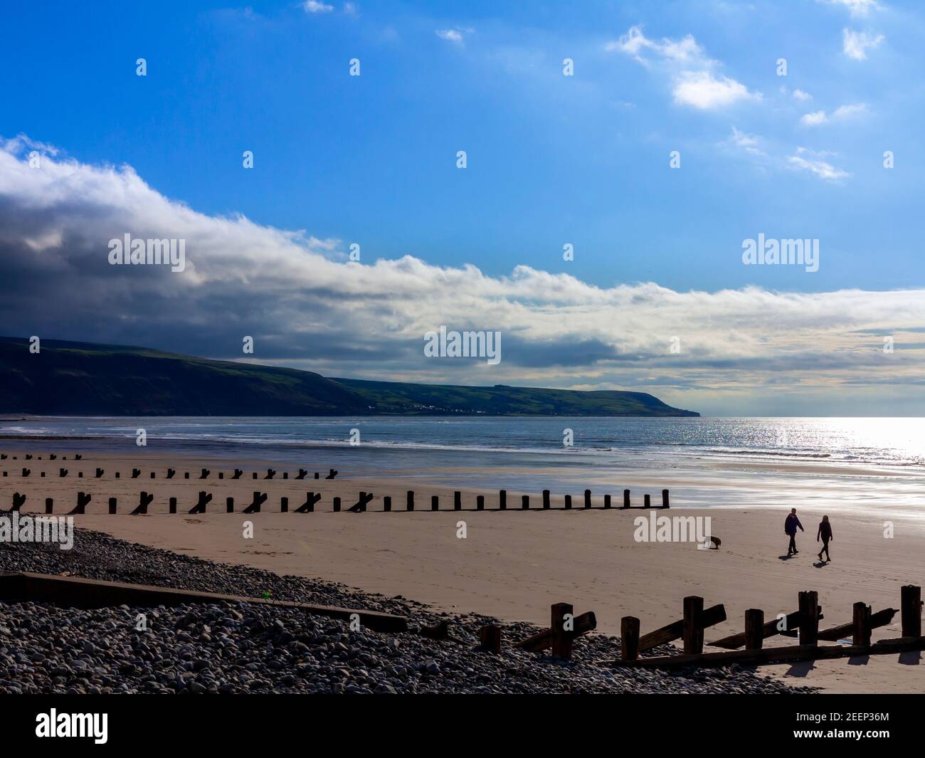 Der Sandstrand in Barmouth Bay oder Abermaw in Gwynedd an der Nordwestküste von Wales mit einem Paar Wanderhund in der Ferne. Stockfoto