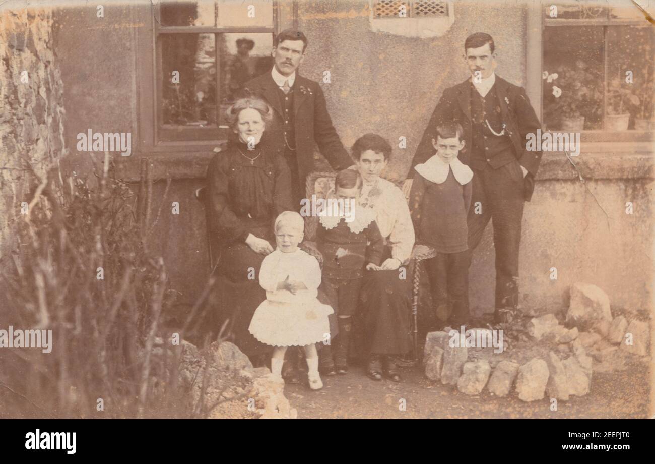 Jahrgang Anfang 20th Jahrhundert fotografische Postkarte zeigt eine Familie Gruppe posiert in ihrem Garten. Stockfoto